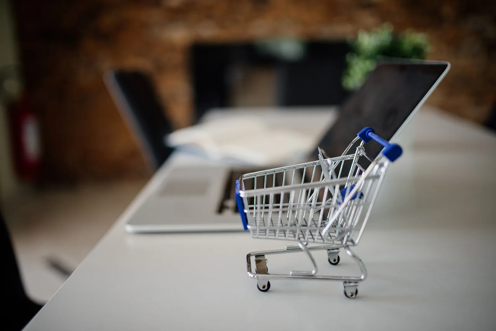 Klein winkelwagentje naast een laptop als symbool voor een webshop