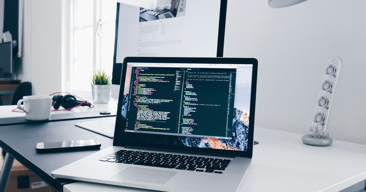 Laptop met code op het scherm op een volle werktafel